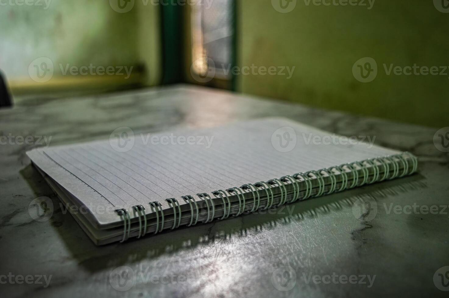 Close up of a spiral notebook with lined paper on a table. The notebook is closed, and the focus is on the binding and the texture of the paper. Concept, education and note taking photo