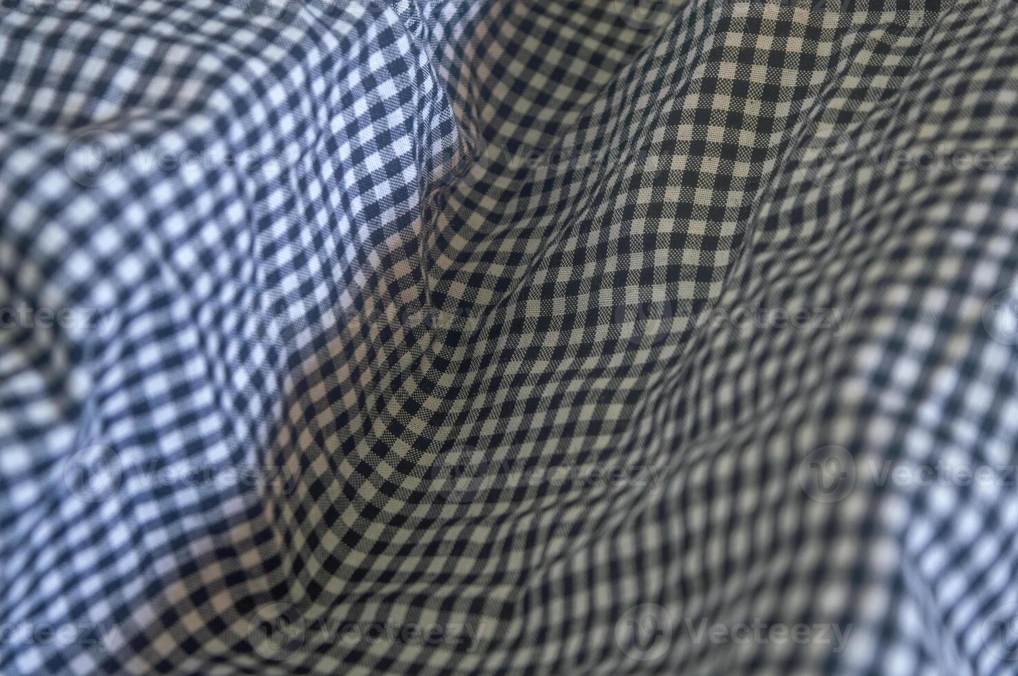 Close up on a blue and white gingham fabric with soft folds, creating a textured and patterned surface. The classic check pattern adds a timeless and versatile feel to the material photo
