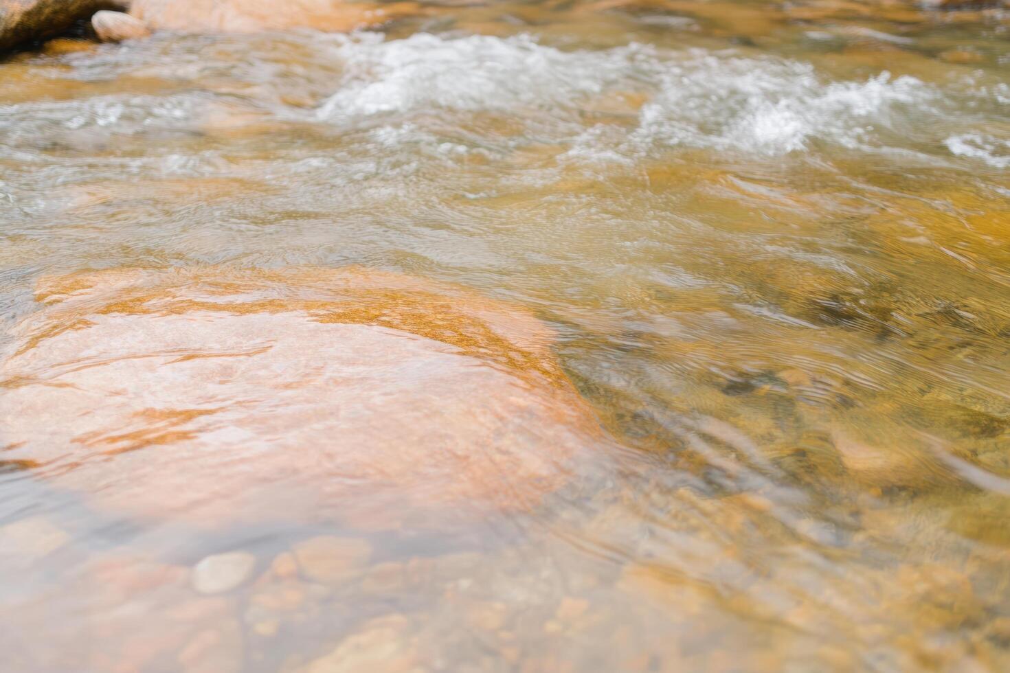 Clear water flowing over smooth rocks in a serene river setting photo