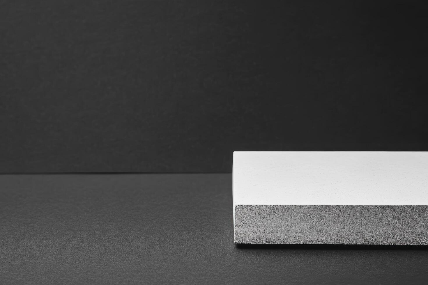 White rectangular object placed on a dark surface in minimalist setting photo