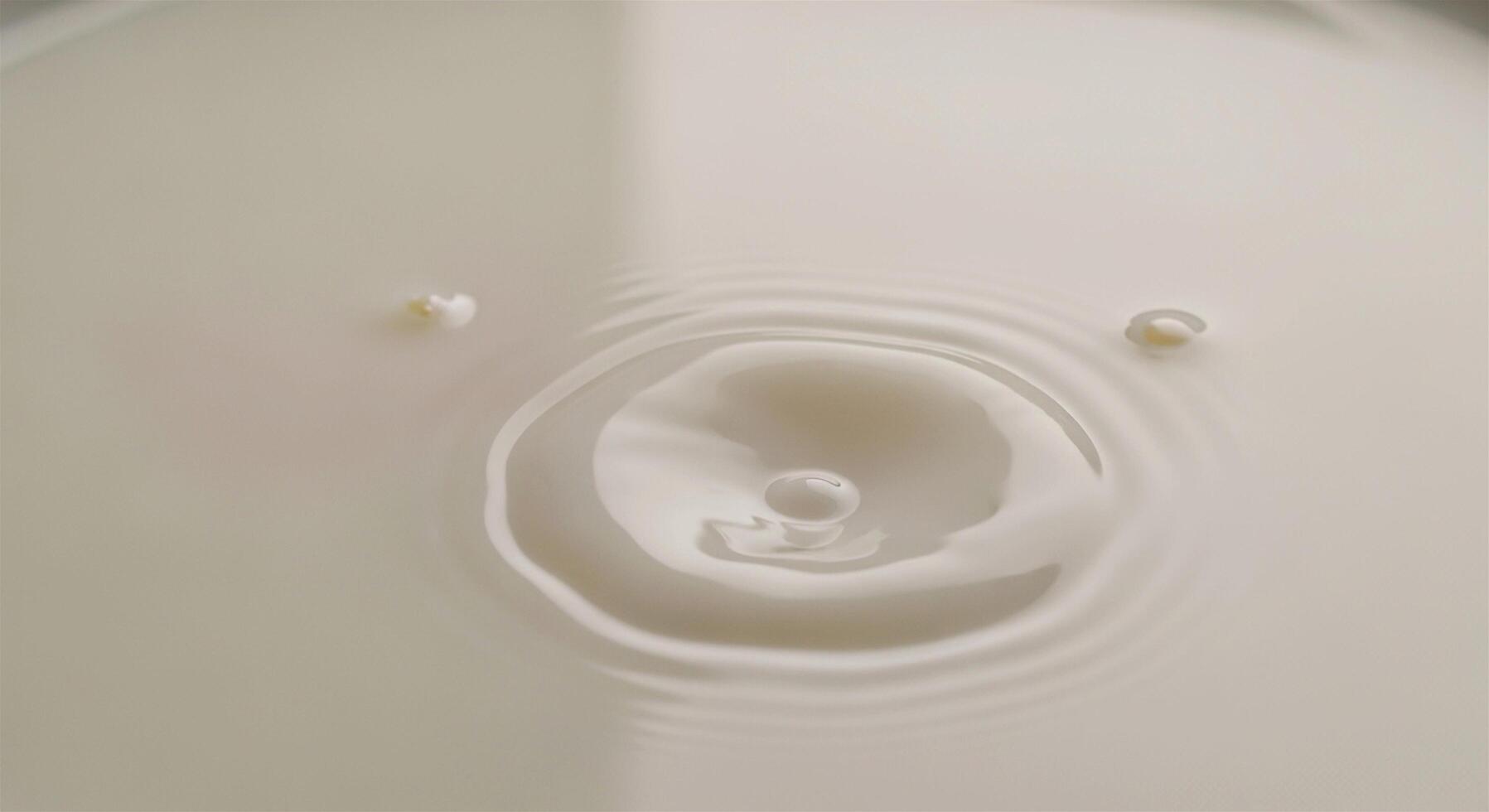 Milk drop creating a ripple effect on a creamy white surface, close-up, high-angle view. photo