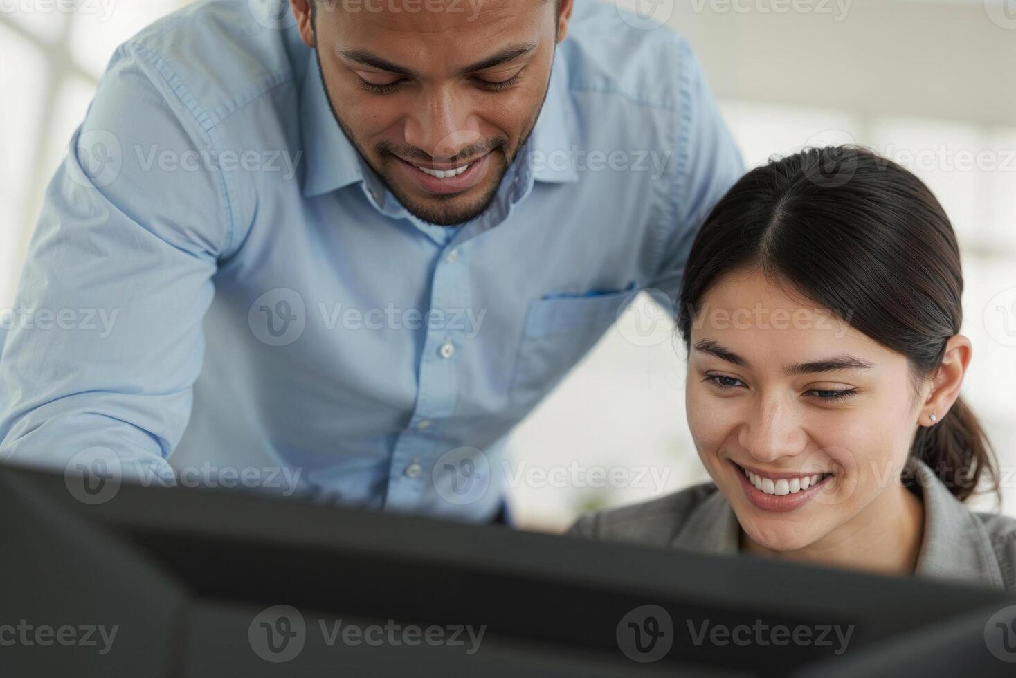 Portrait of two happy students or intern working at a computer screen at project at workplace in office photo