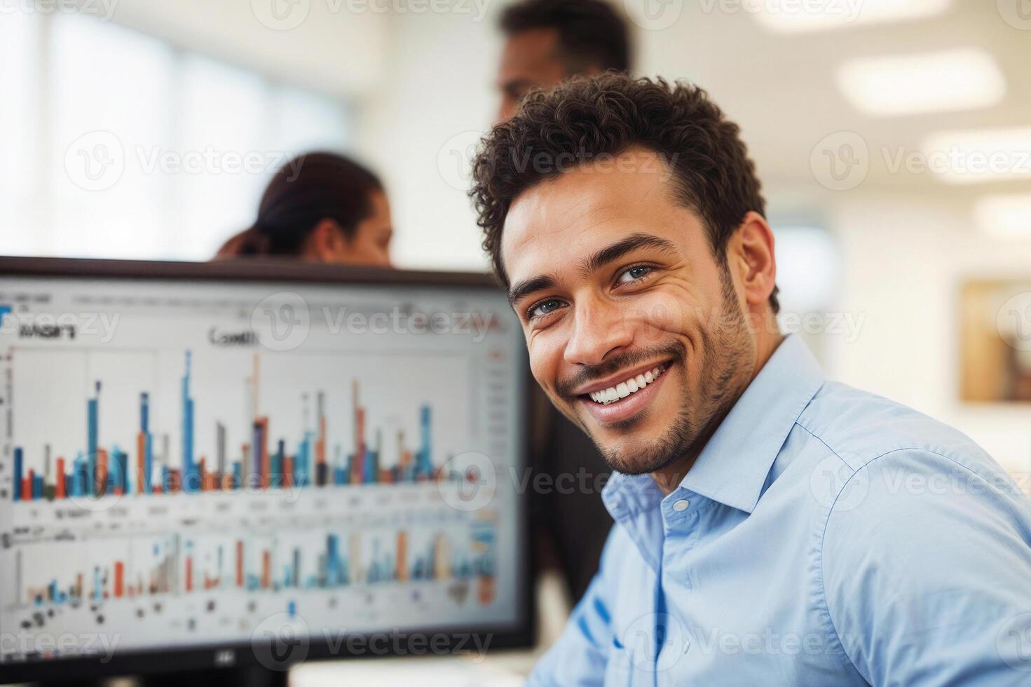 Portrait of happy financial broker is smiling in front of a computer monitor with charts in office photo