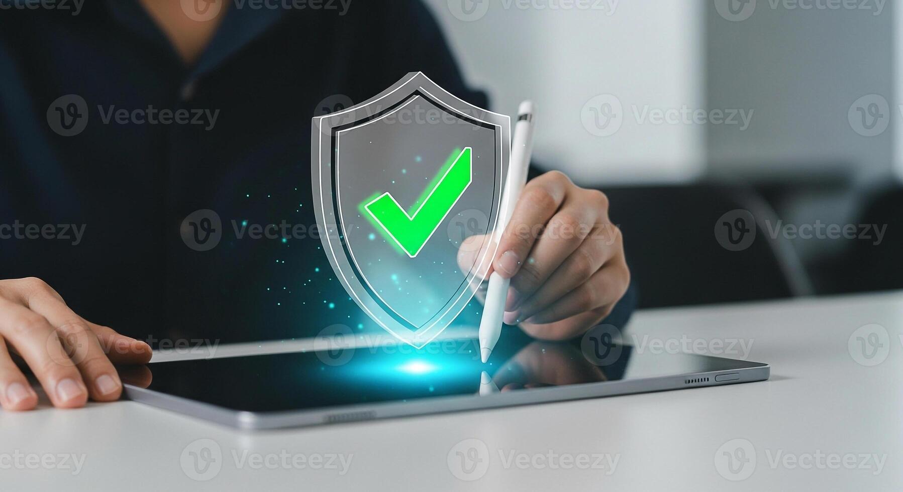 Person using stylus on digital tablet activating a holographic shield with check mark, signifying security and data protection in modern office photo