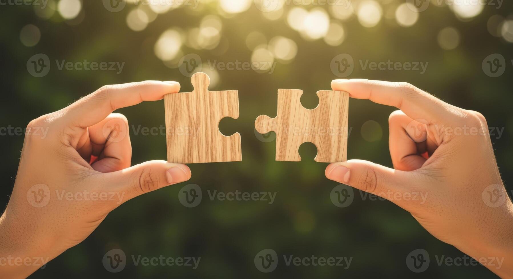 Hands Connecting Two Wooden Jigsaw Puzzle Pieces Against a Blurred Green Background Symbolizing Unity and Solutions photo