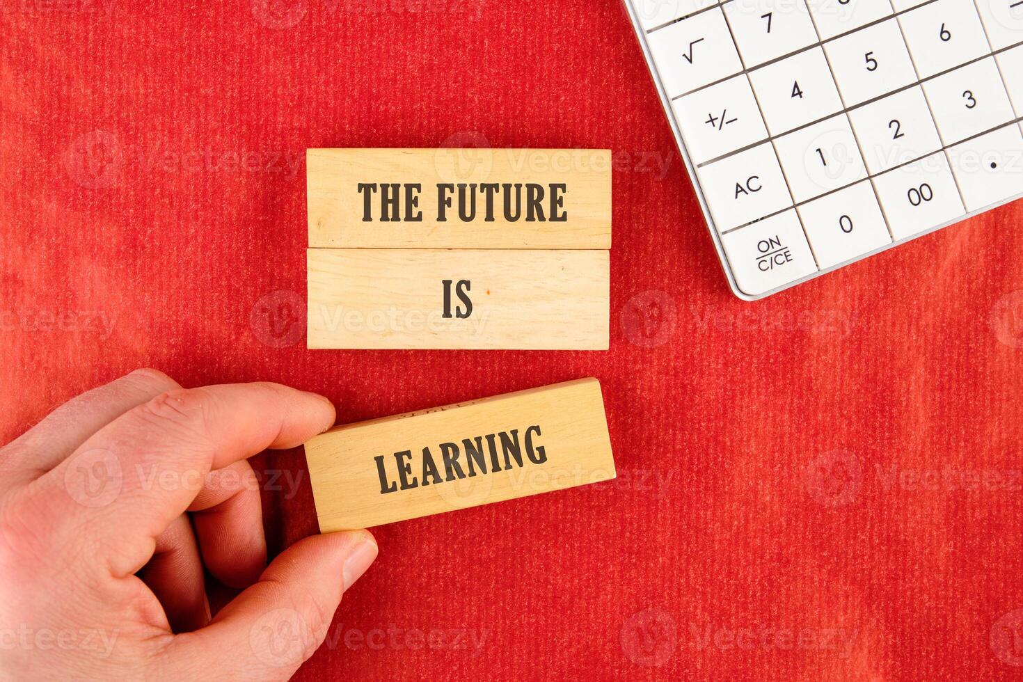 Concept of Intelligence, science and mind. THE FUTURE IS LEARNING assembled from blocks in a composition with part of a white calculator and a hand, top view photo