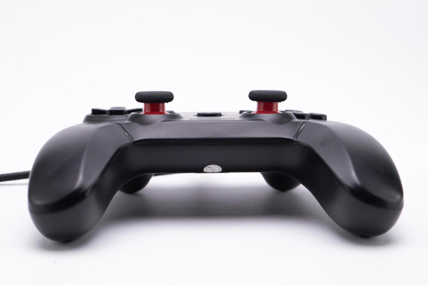 Black Game Controller with Red Joysticks on White Background Close-up View. photo