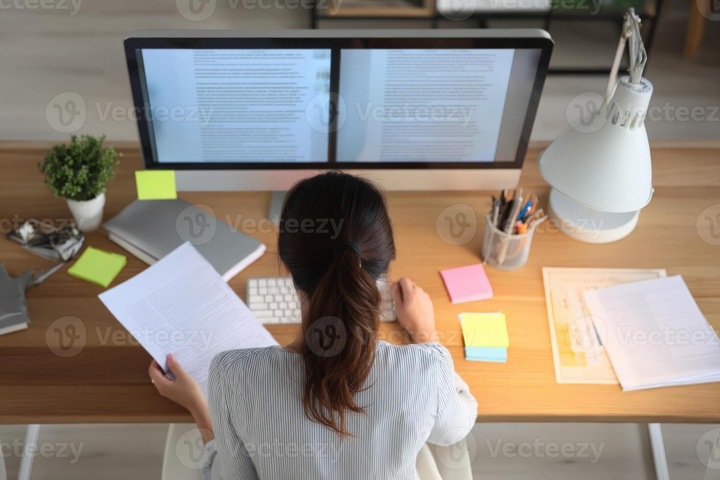 Woman Working at Computer Desk, Reviewing Documents and Analyzing Data for Business Strategy photo
