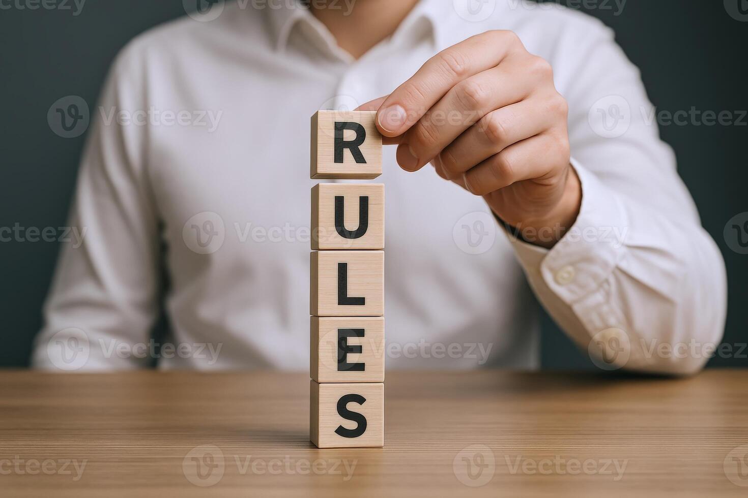 Man Stacking Wooden Blocks Spelling Rules on a Wooden Table, Emphasizing Regulation and Guidelines photo