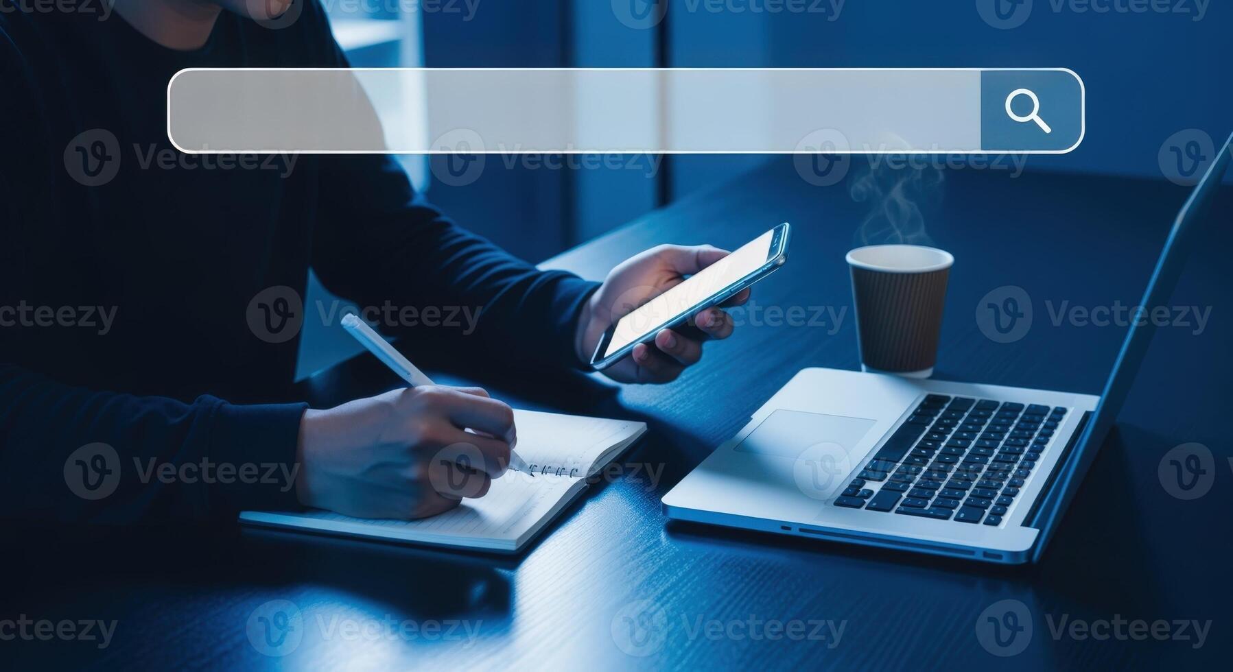 Person working at desk with a smartphone, laptop, and notebook, with search bar overlay, in a blue tone photo