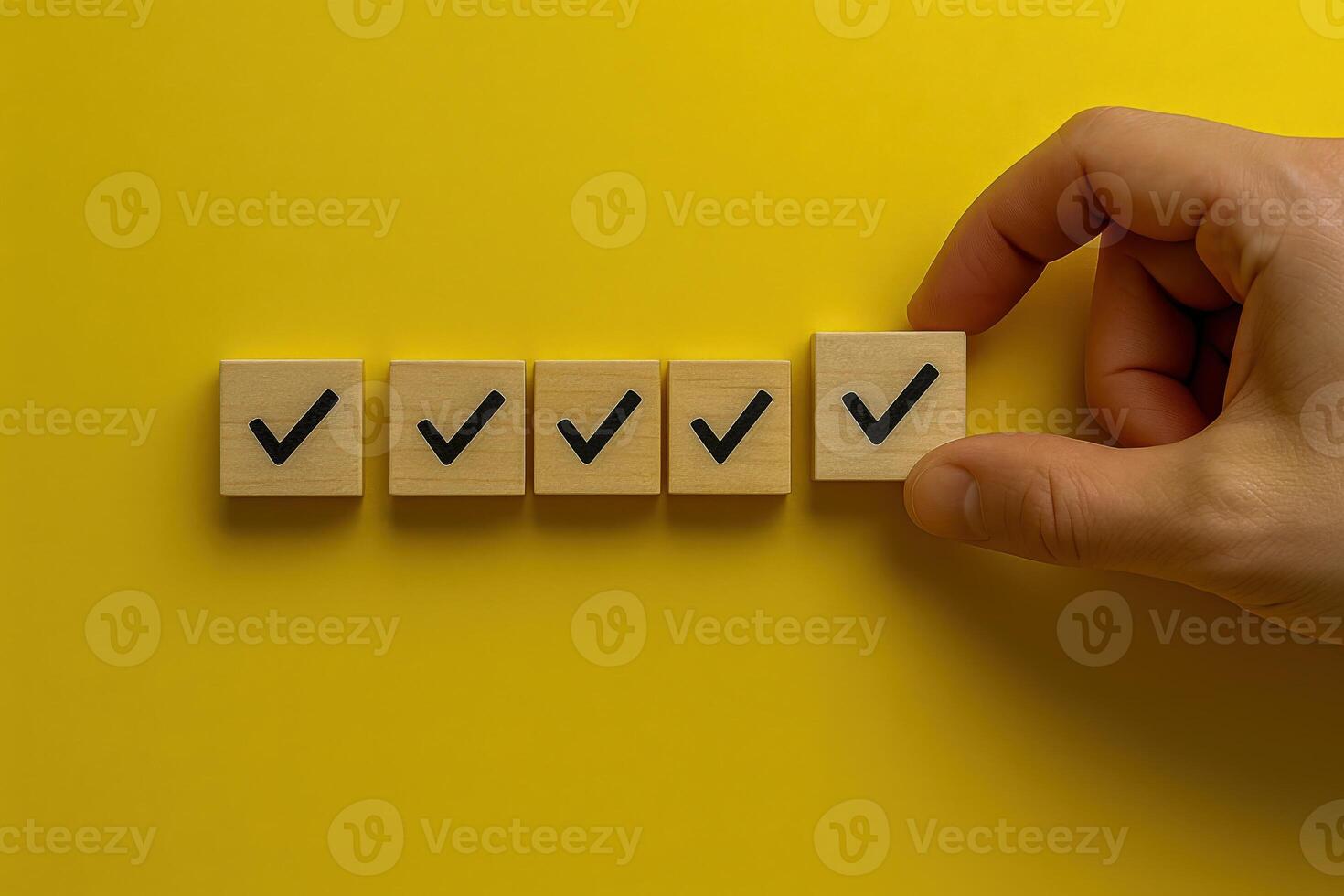 Checkmark on Wooden Block Arranged in a Row with Hand on Yellow Background, Concept of Checklist photo