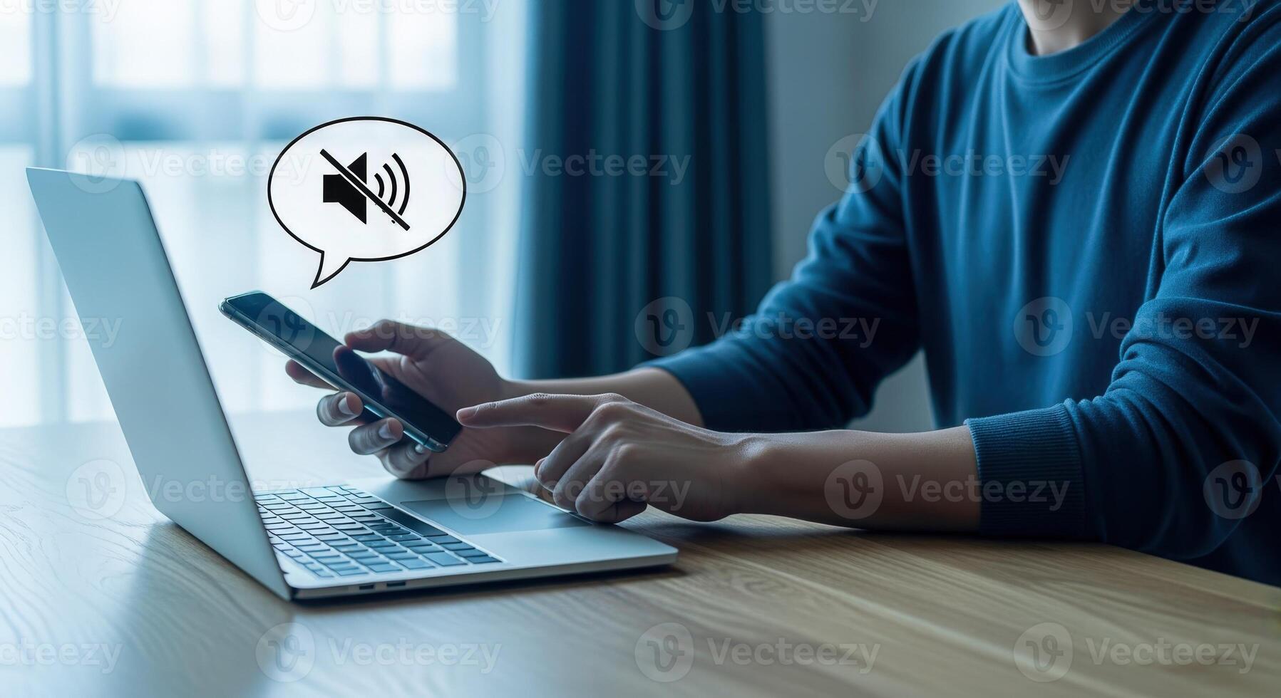Man Using Phone with Mute Notification Bubble While Working on Laptop, Focusing on Productivity photo