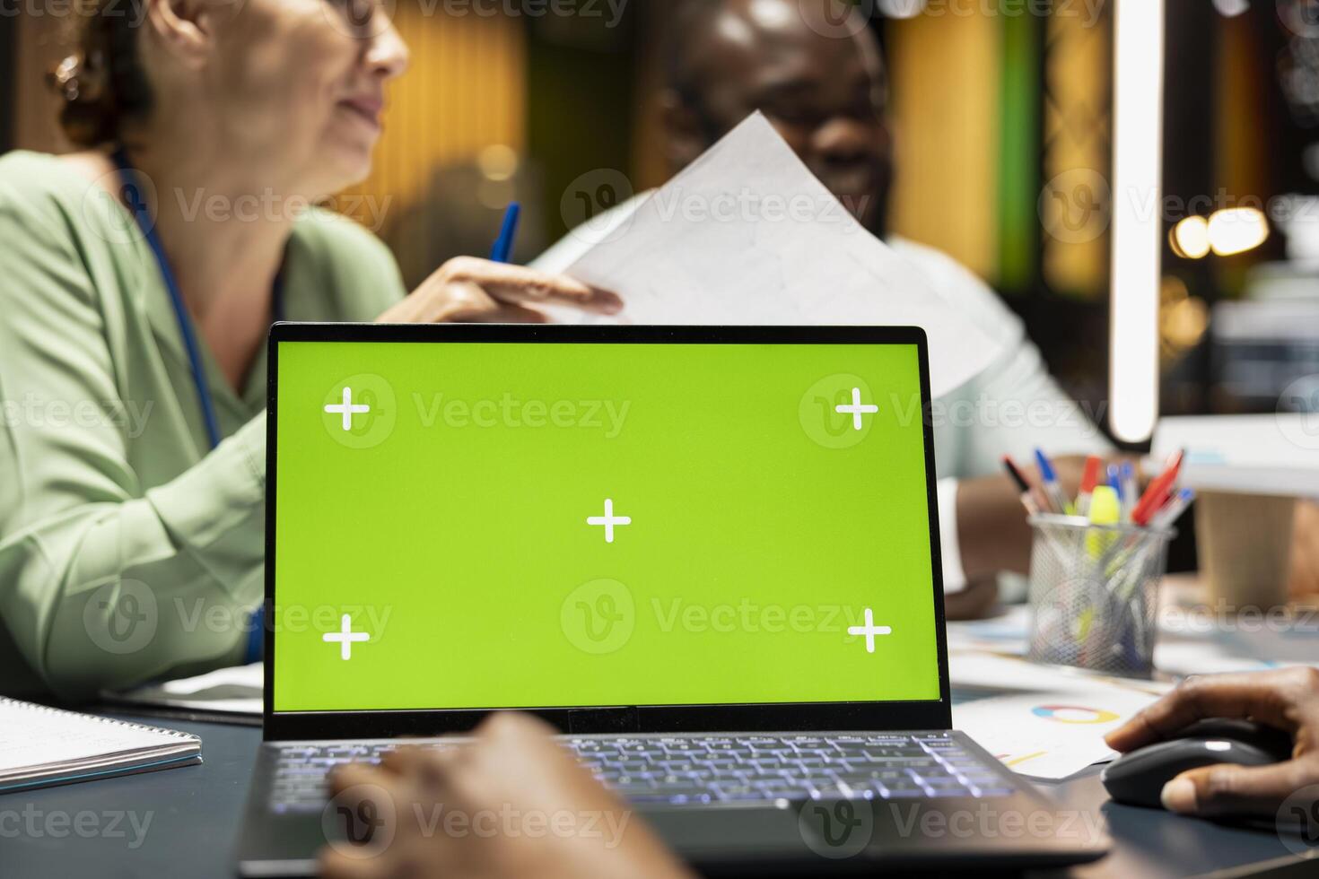 Company associates briefing after hours next to chroma key screen, experts group exchanging insight with files and establish project objectives. Performance summary for goals presentations. photo