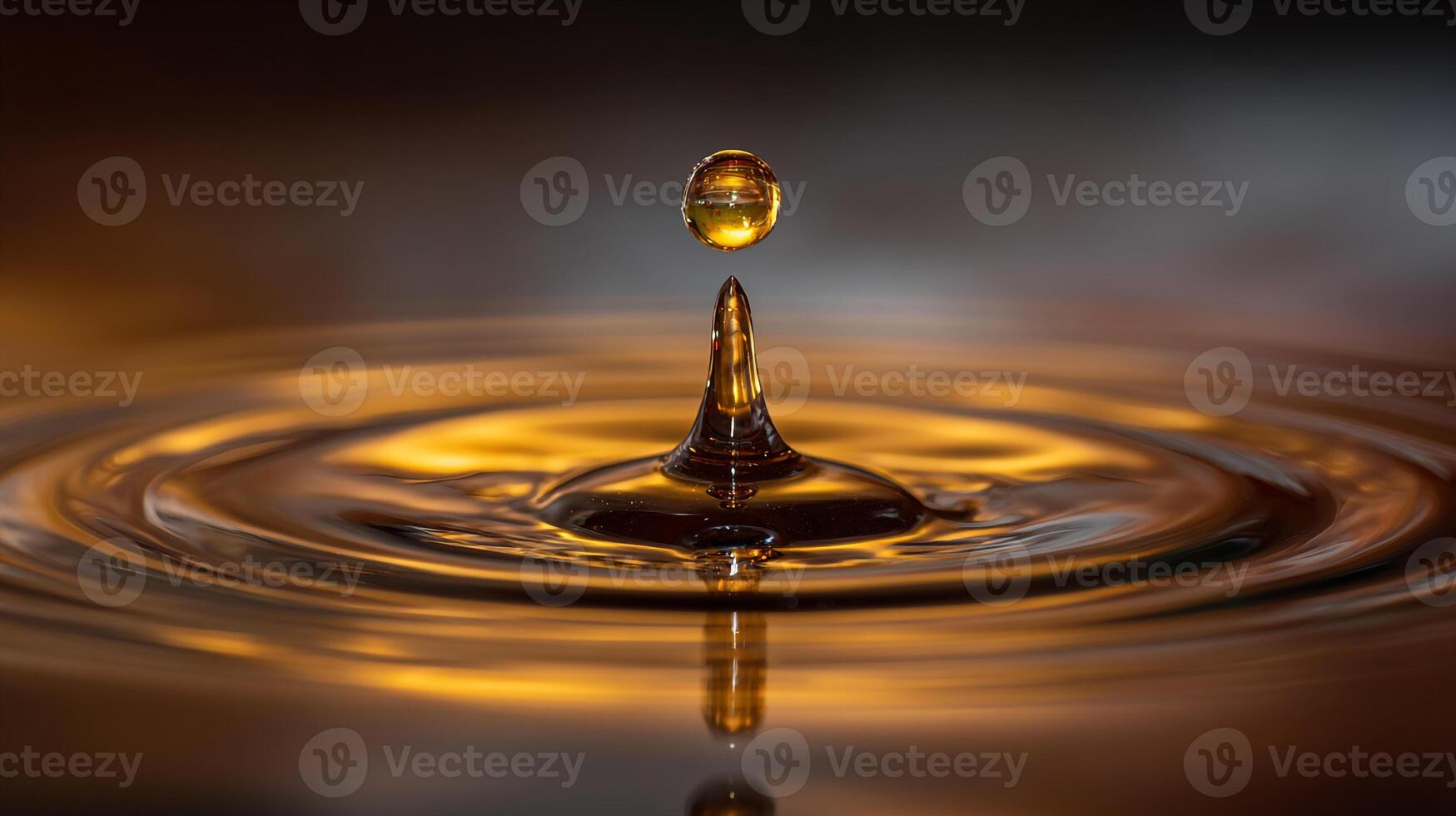 A single drop of golden liquid falls into a pool, creating ripples and splashes in a mesmerizing slow motion effect photo