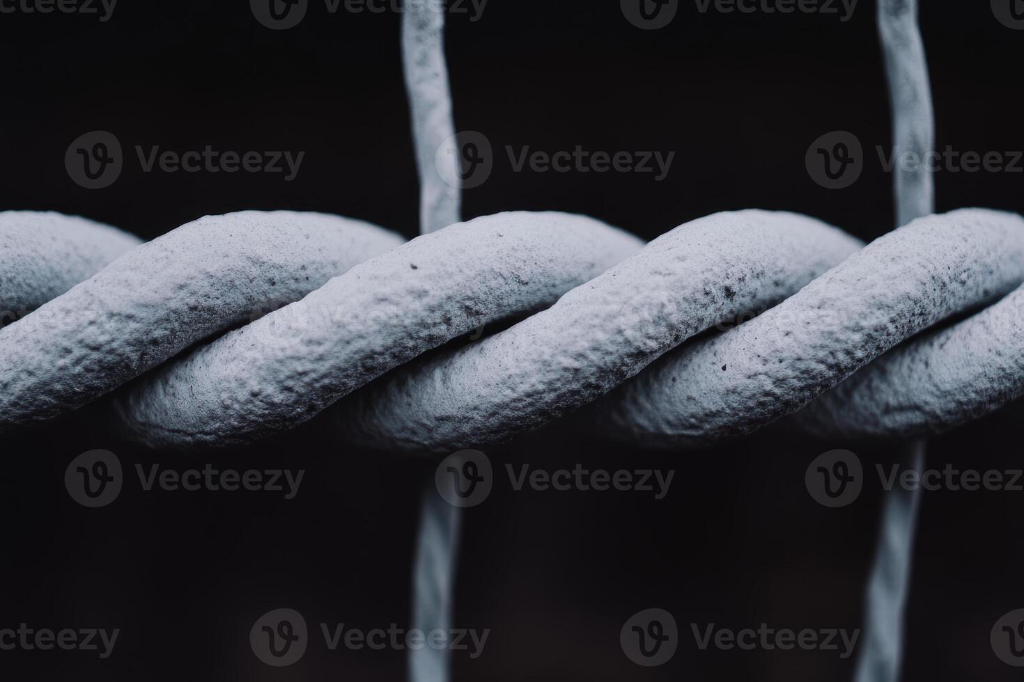Close-up view of textured gray rope twisting against a dark background photo