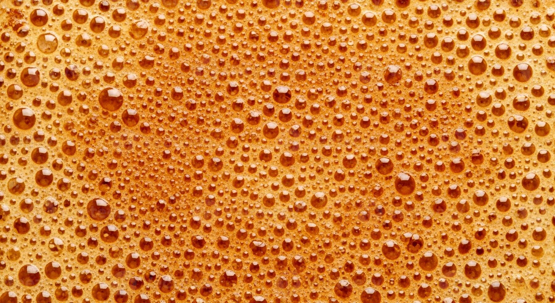 Macro view of golden brown foam with many small bubbles creating an abstract texture. photo