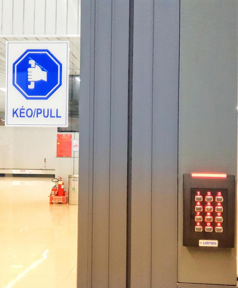 Hanoi, Vietnam on 13 May 2025. Entering Building Using Keypad and Pulling Door photo