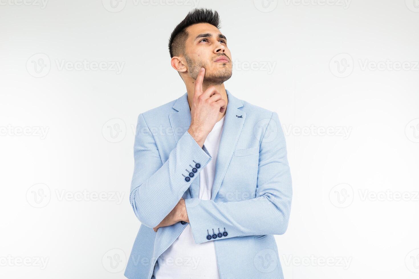 charming man in a blue classic jacket thinks of a solution and a problem on a white background with copy space photo