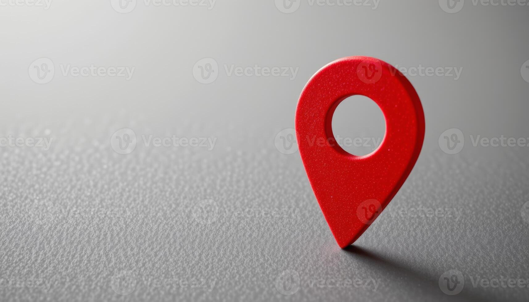 Single bright red map pin pointing downward on a textured gray surface leaving ample space on the left photo