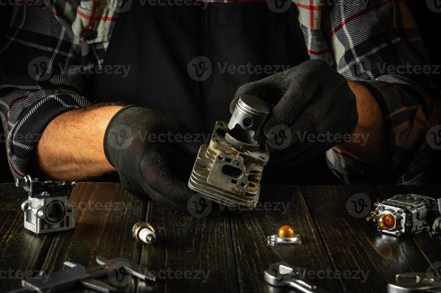 Restoring a chainsaw engine after a breakdown. A mechanic repairs an engine on a table in a workshop photo