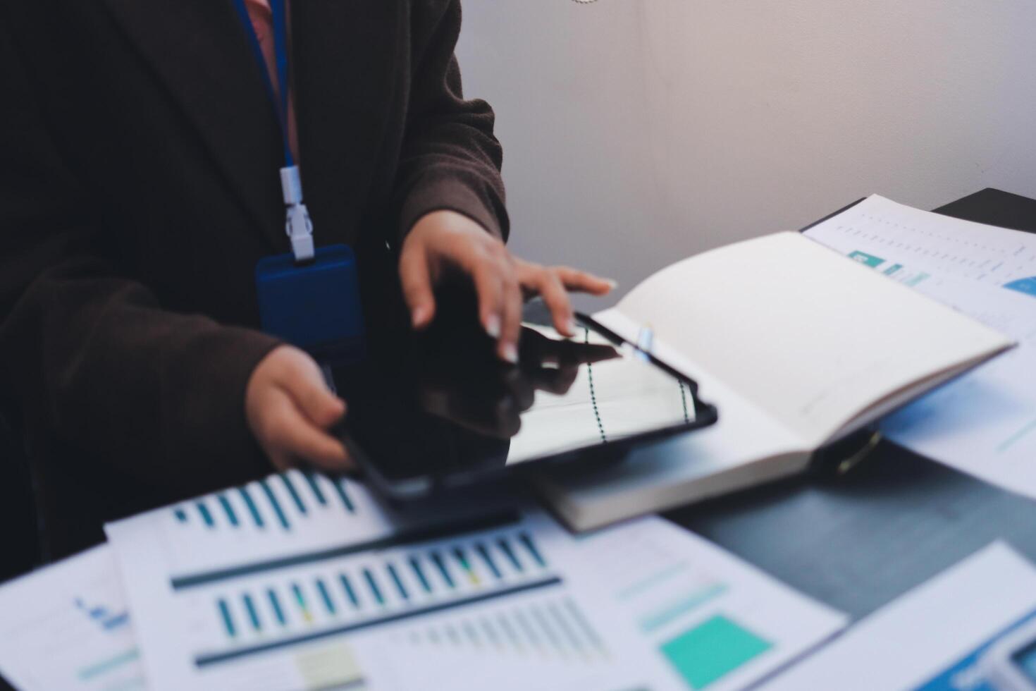 A person using a tablet computer with papers and graphs photo