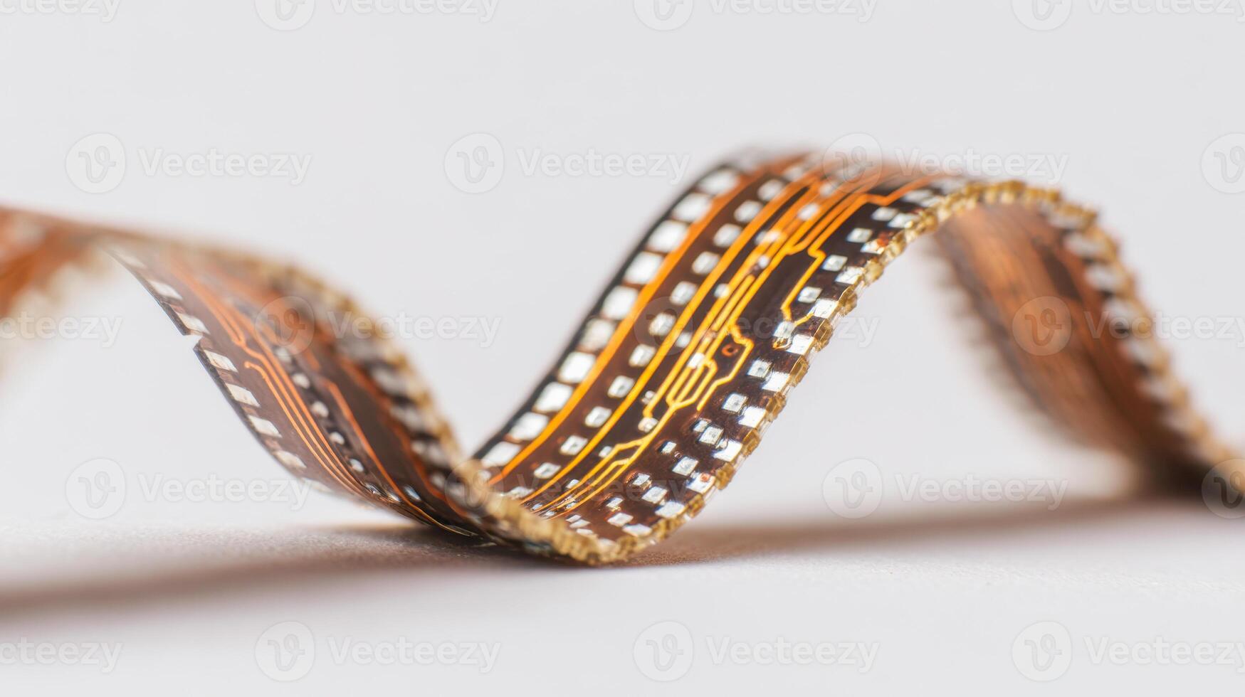 Flexible printed circuit board with detailed electronic pathways and components forming smooth curves on a neutral background for advanced technology concepts photo