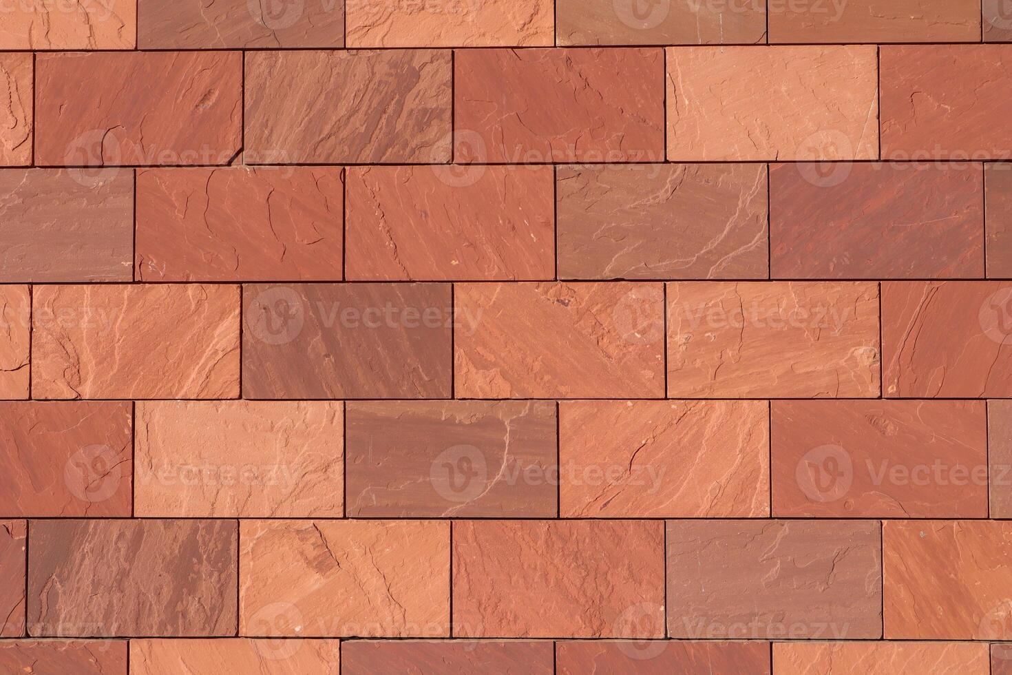 Abstract full-frame close-up of a wall of brown, terracotta-colored, and reddish rectangular bricks, showcasing their varied textures and hues in a precise, geometric pattern. photo