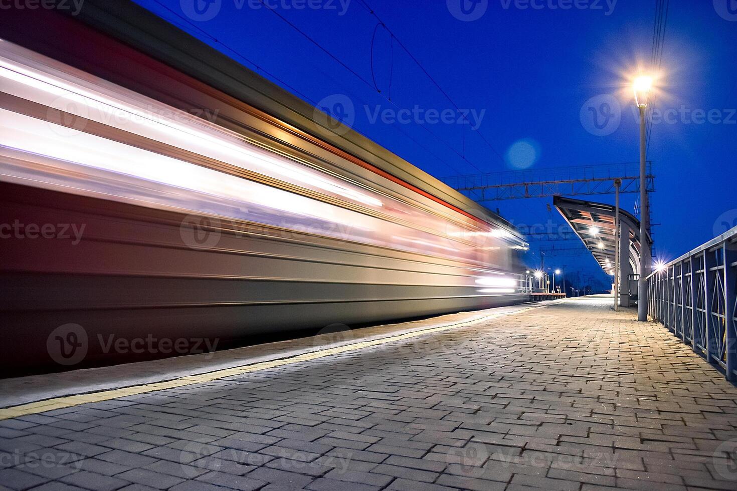 Evening arrival of the train on an empty platform. . Photo taken with a shutter speed. Rays of light. Blur. Evening railway station.