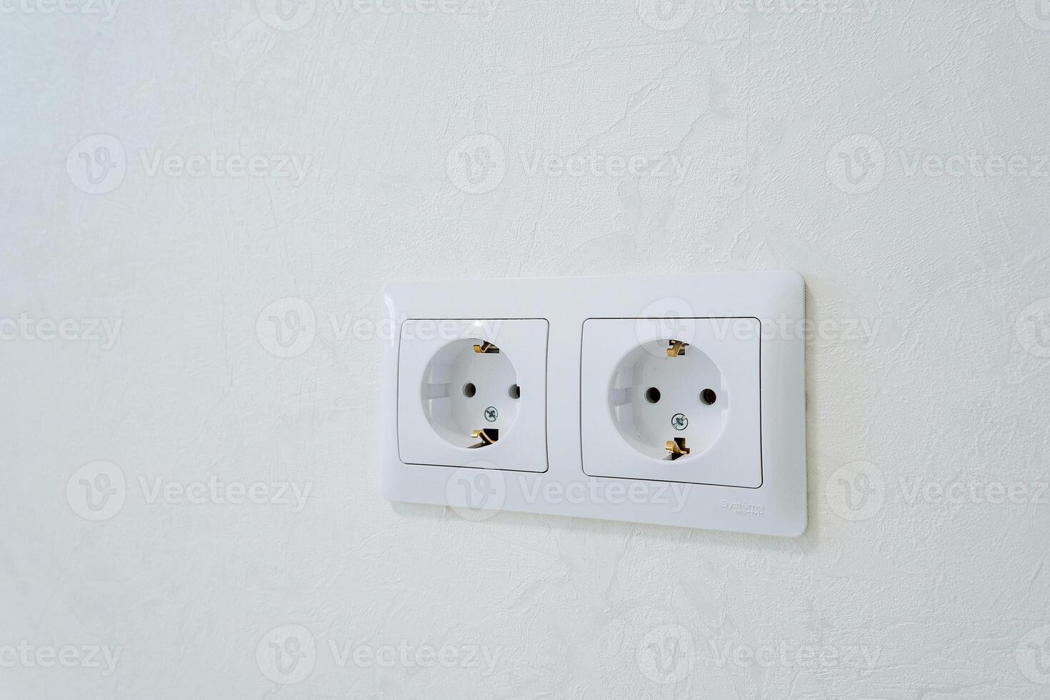 There are two white electrical outlets that have been strategically installed on a clean, white wall for efficient use. These outlets provide necessary access to electrical power photo