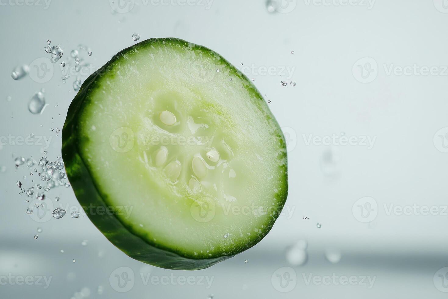 A slice of cucumber is being splashed with water photo