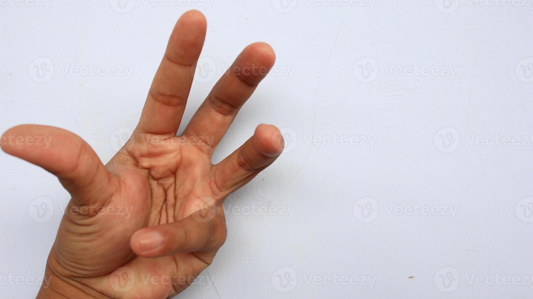 Hand displays the number three against a white wall, symbolizing counting or a third option with a simple, clean aesthetic. photo