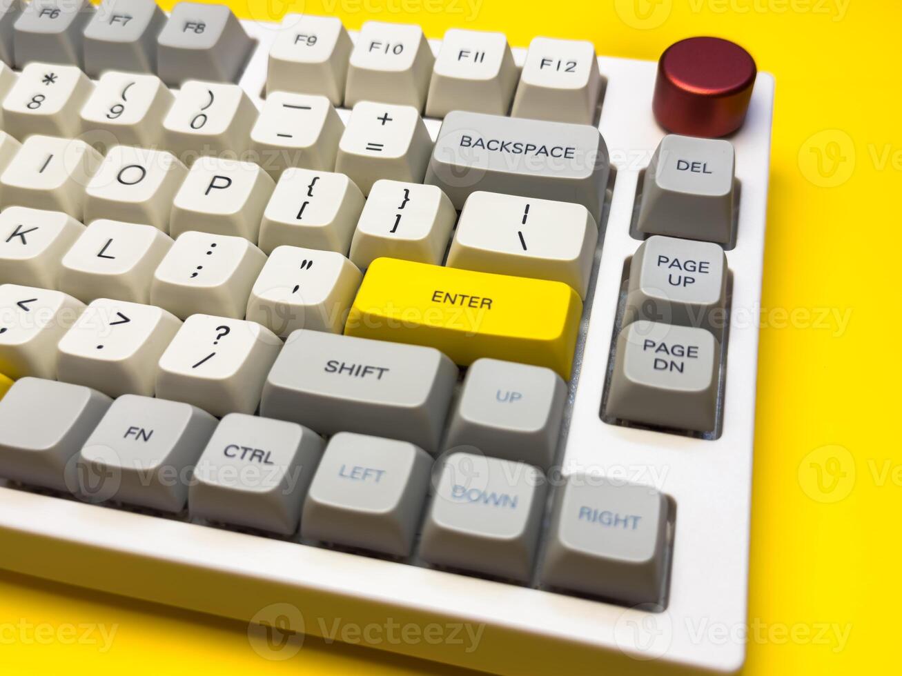 White mechanical keyboard with bright Enter key on bright yellow background, minimalism, keyboard buttons. A keyboard with a yellow key on the bottom left photo