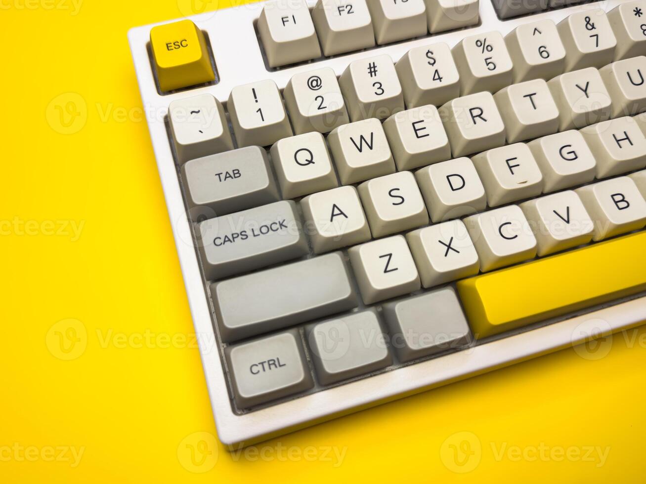 Close up White mechanical keyboard with bright Esc key on bright yellow background, minimalism, keyboard buttons. A keyboard with a yellow key on the bottom left photo