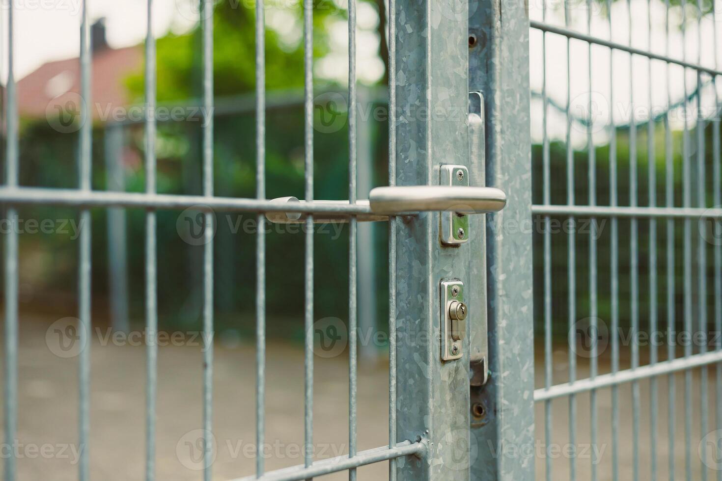 This is a CloseUp Image Featuring a Silver Metal Gate That Includes a Lock and Latch Mechanism, Surrounded by Lush Greenery Perfect for Visual Concepts Related to Security and Access Control photo