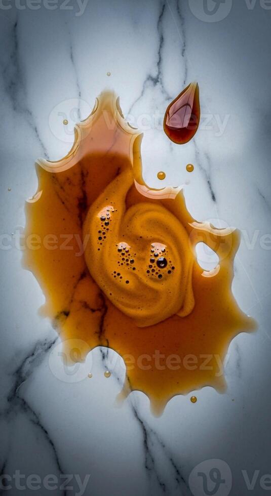 A dynamic splash of amber liquid with swirling patterns and bubbles on a textured marble surface photo