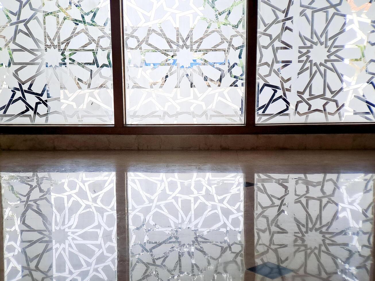 Geometric patterns reflect from the window onto the marble floor creating a repeating symmetry photo