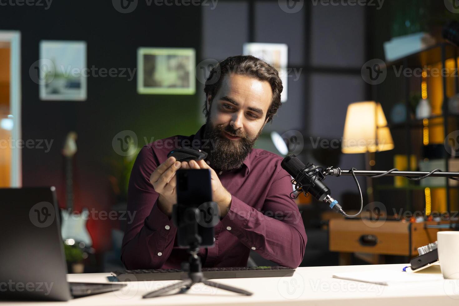 Content creator excited about newly launched wireless mouse, feeling impressed by high quality sensitivity. Joyful man trying out office computer peripheral, filming using smartphone on tripod photo