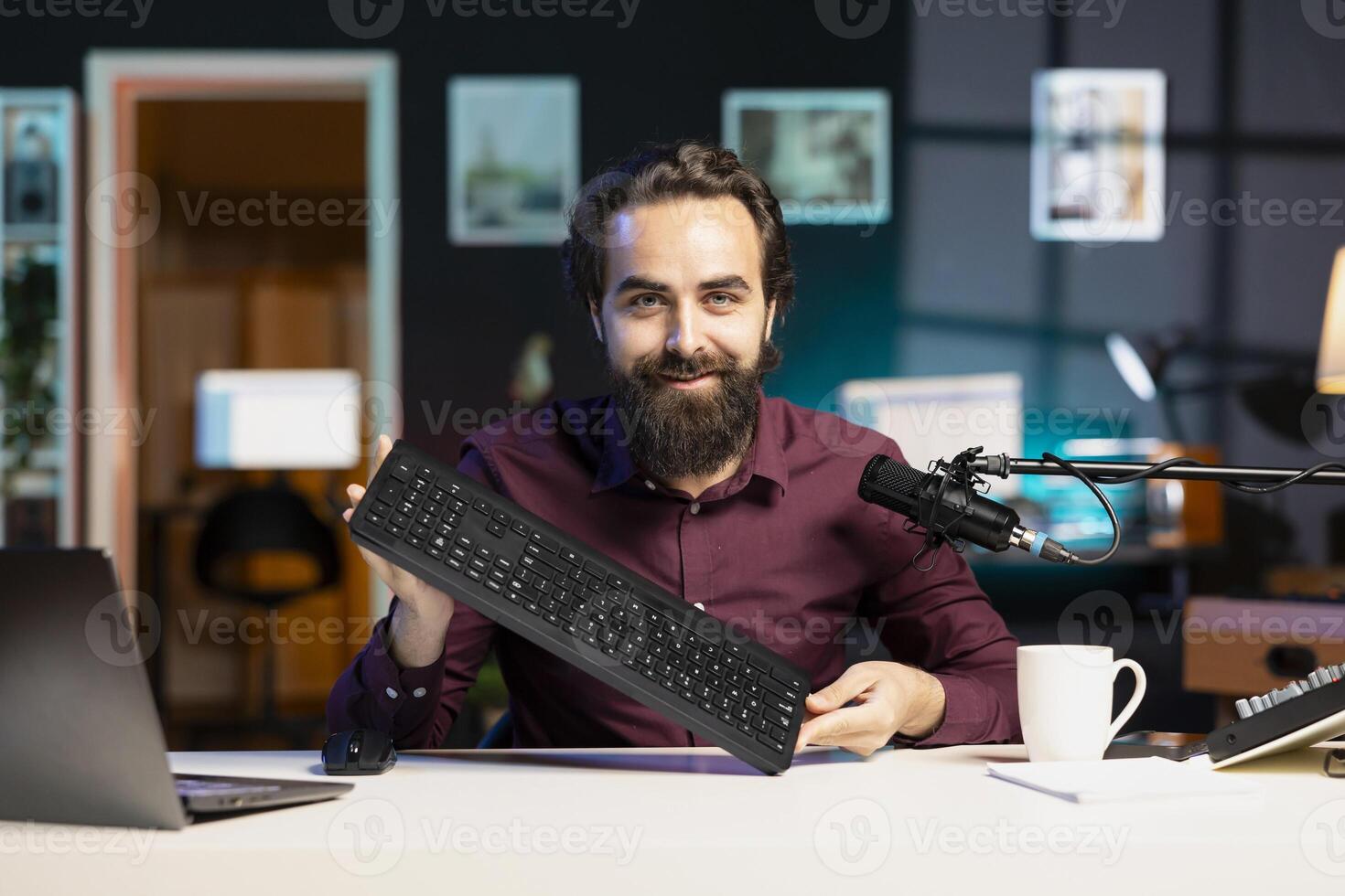 Smiling content creator filming keyboard review in personal studio, ready to start testing it. Cheerful technology guru showcasing computer peripheral to audience on niche online channel photo