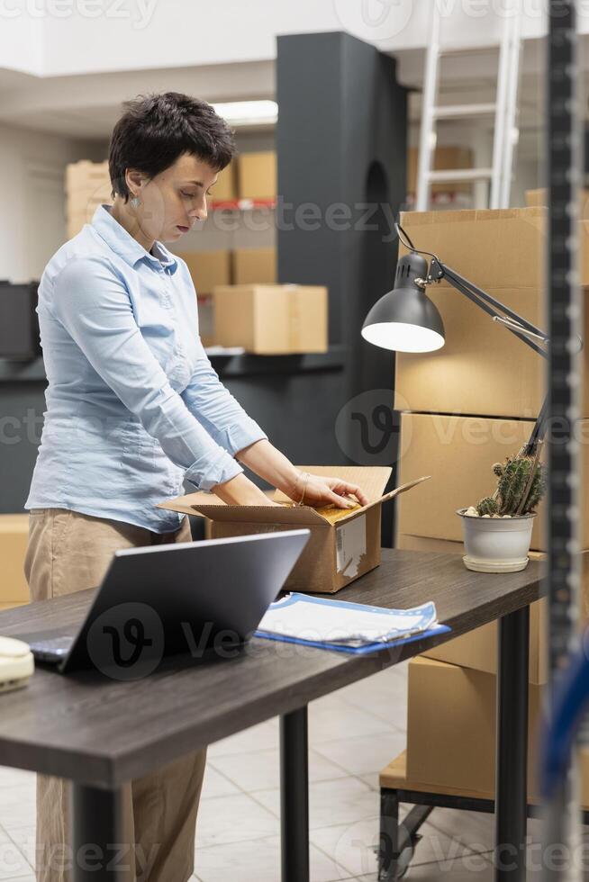 Warehouse employee managing factory operations in a local storage room, processing orders and handling packages to ensure efficient distribution of merchandise. Small business. photo