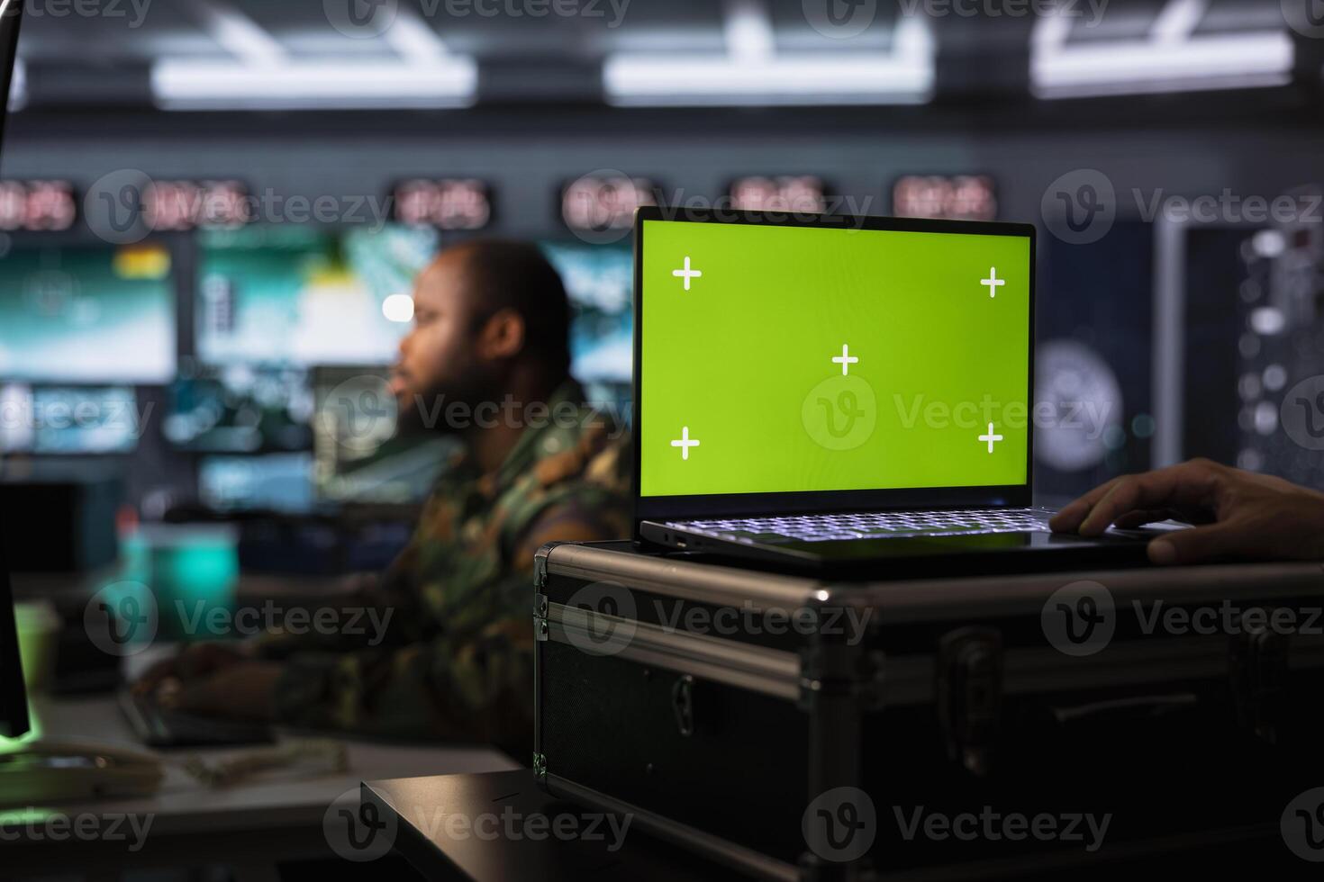 Combat specialist working on green screen laptop in surveillance monitoring center filled with digital equipment. Intelligence corps doing job in base of operations using chroma key notebook photo
