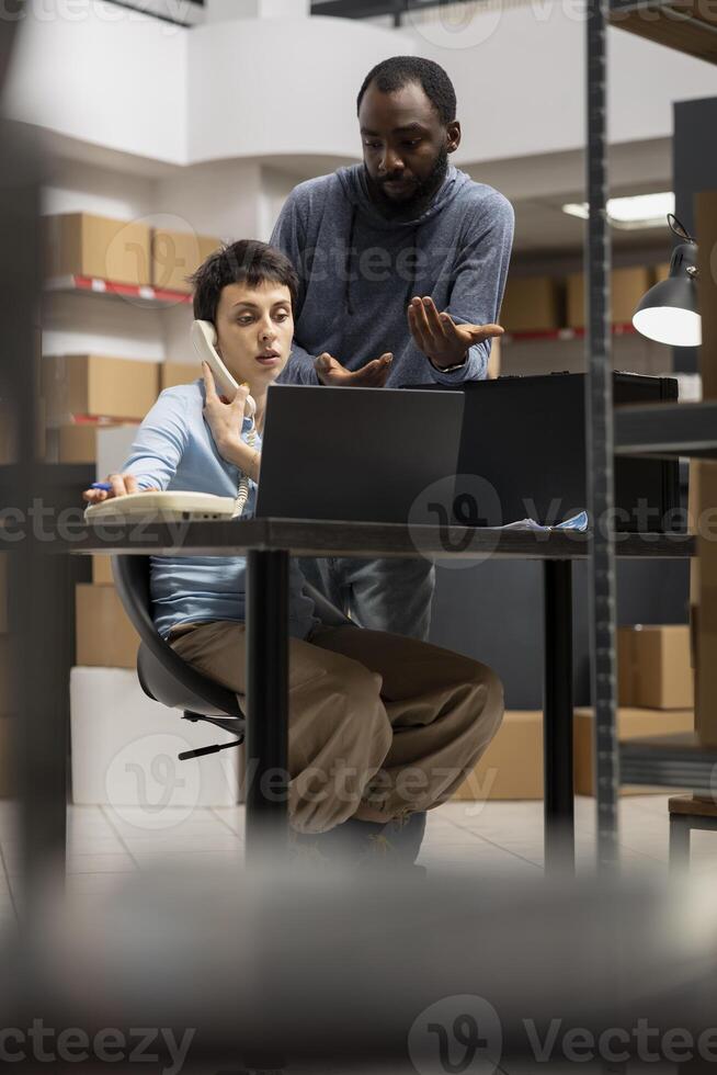 Diverse team uses inventory room logistics for order processing, coordinating logistics in a small warehouse. Solving business operations and tasks of a local delivery company. photo
