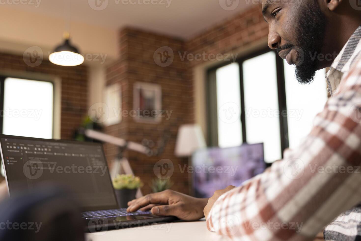 Focused software developer typing code on laptop during remote work session. IT freelancer working on app development and practicing software engineering data in home office environment. photo