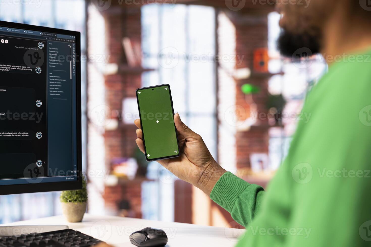 Man holding mockup phone solving personal tasks with AI LLM chatbot answering prompts. Person using green screen smartphone and computer to interact with large language model program photo