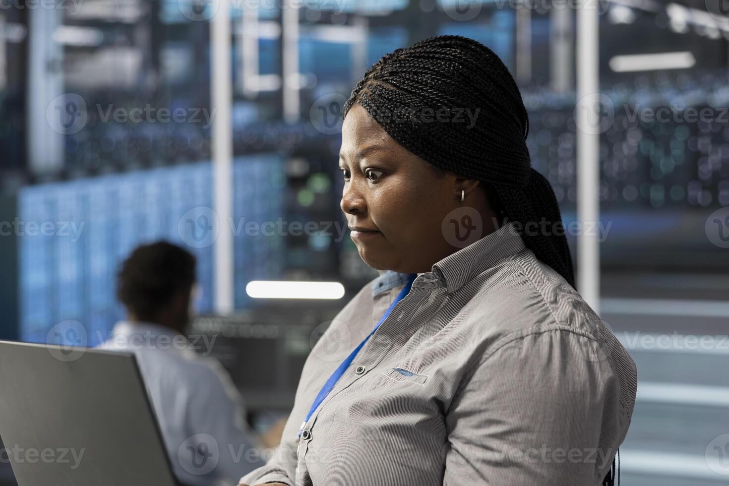 Engineer using notebook device to oversee data center machines processing workloads. African american woman doing maintenance on server rigs tasked with solving complex operations photo