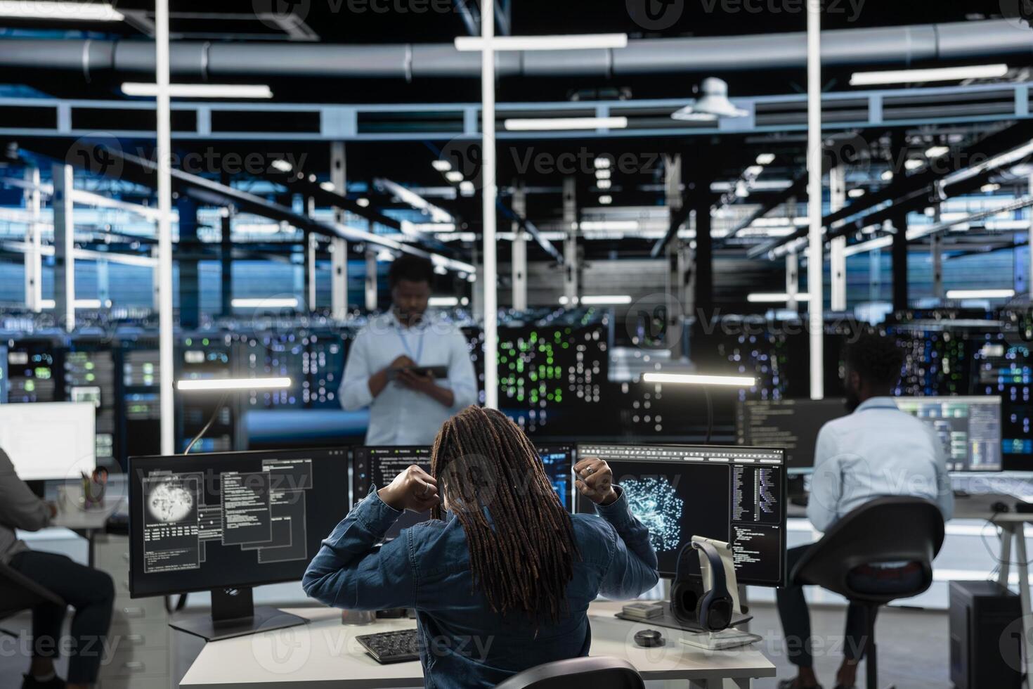 Fatigued data center worker stretching at desk, using machine learning algorithms to analyze datasets. Tired server farm engineer relaxing muscles, using AI to recognize data patterns photo