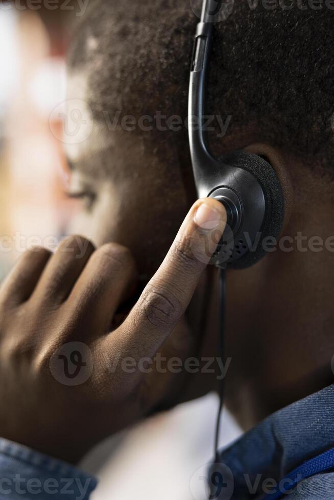 Call center agent speaks with customer using audio headset, adhering to company communication guidelines, close up. African american customer support worker follows call script during chat with client photo