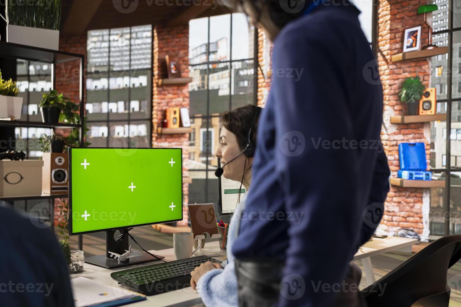 Call center agent using remote access tools on green screen PC to connect to customer devices, fixing errors. Worker in customer center using chroma key computer, installing software for clients photo