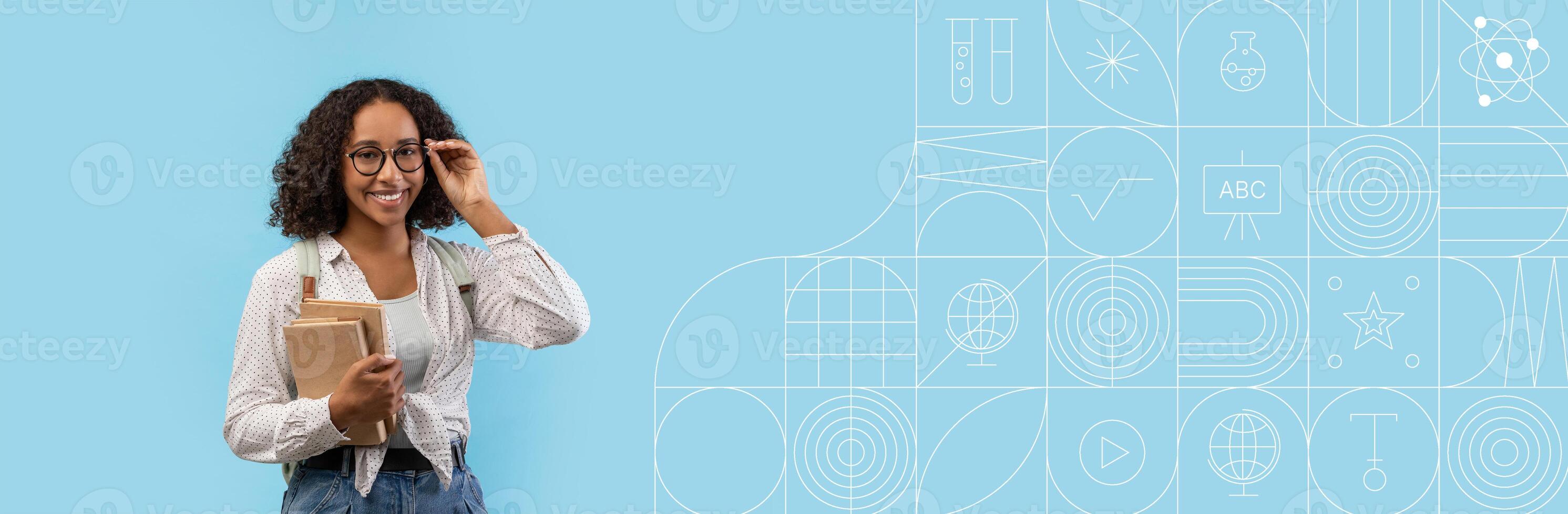 A student stands confidently with a stack of books and a notebook, smiling while adjusting her glasses. The vibrant background is ideal for an educational banner, providing ample copy space. photo