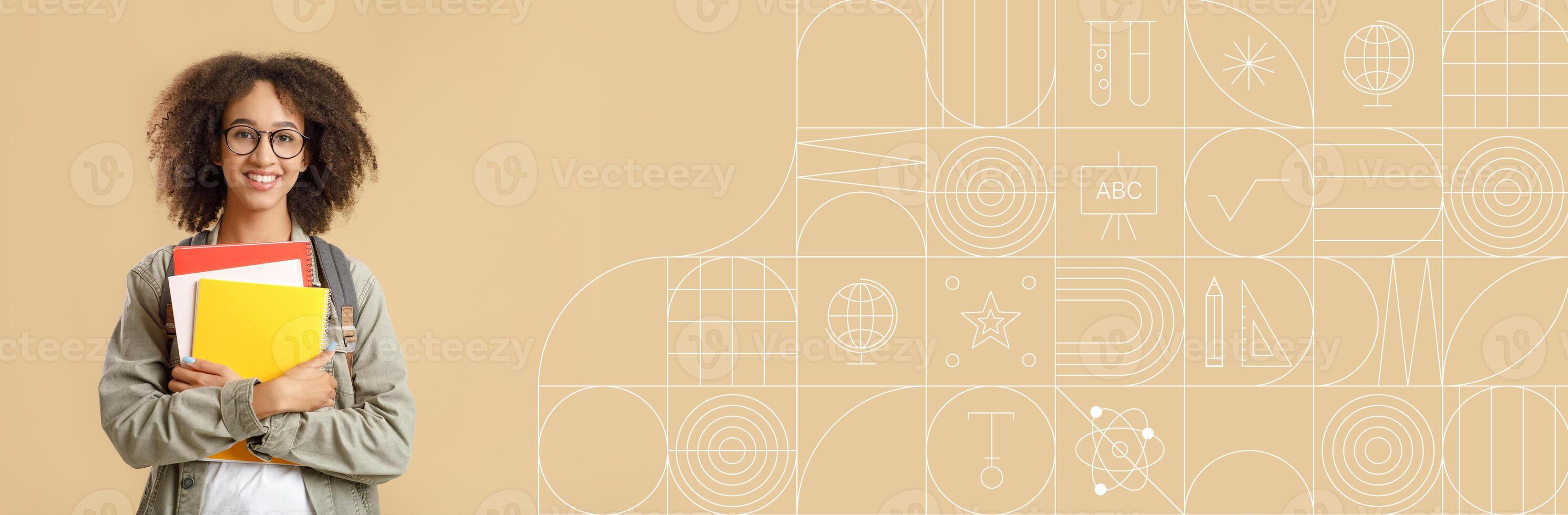 African American student stands confidently with a stack of colorful books, smiling while showcasing an environment designed for learning and creativity. Ideal for promoting educational content. photo