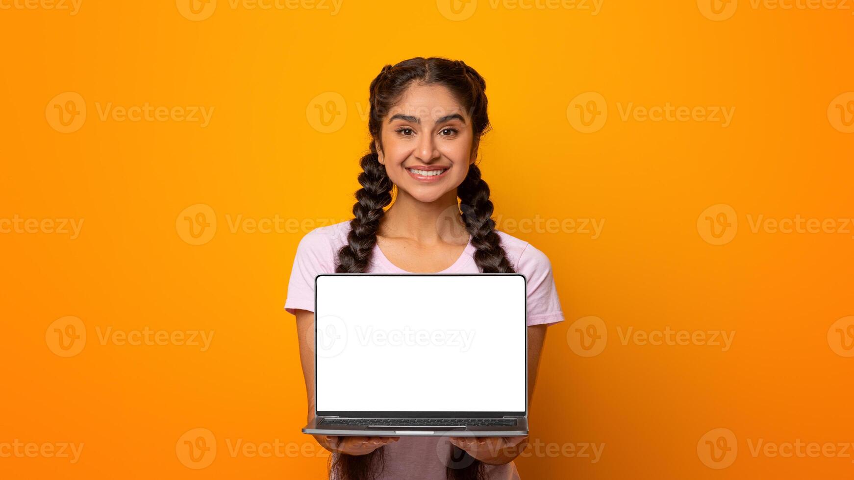 Great Website. Smiling Indian Lady Holding And Showing Laptop Computer With Empty Screen To Camera, Posing Standing Over Yellow Studio Background. Digital Display, Mockup For Advert photo